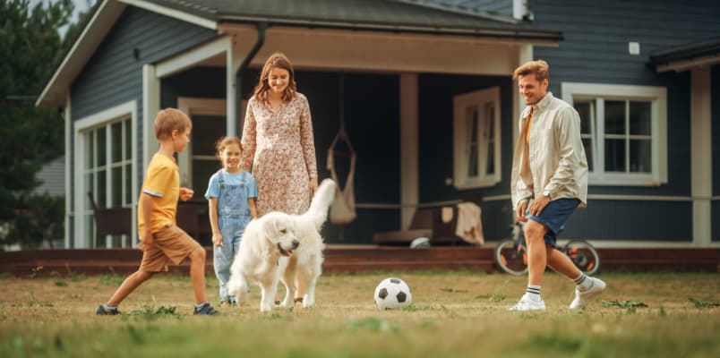 一个家庭带着一只狗在外面玩足球。