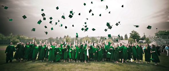 穿着学位服的成功毕业生，举起他们的帽子。