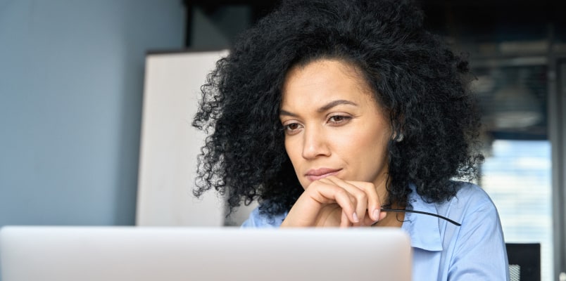 一个黑色头发的女人,看着她修改返回信息的笔记本电脑。