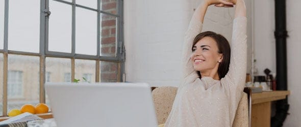 一名妇女在网上填写完纳税申报单后伸展双臂。