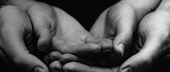 黑白照片，一个男人张开双手，握着一个孩子张开的手