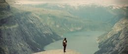 旅行家女孩背着背包站在山间，欣赏山谷