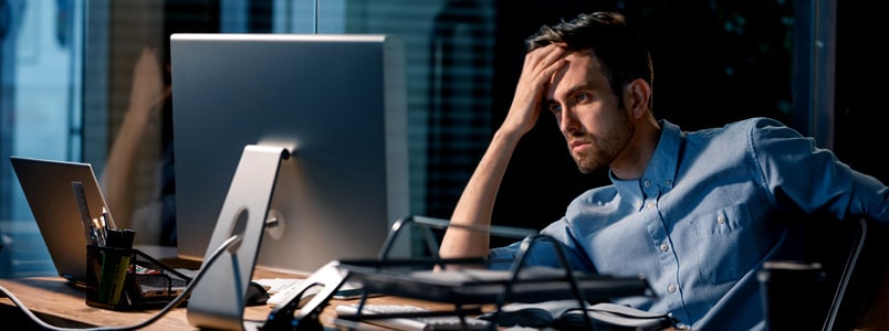一个男人坐在电脑前，手放在额头上